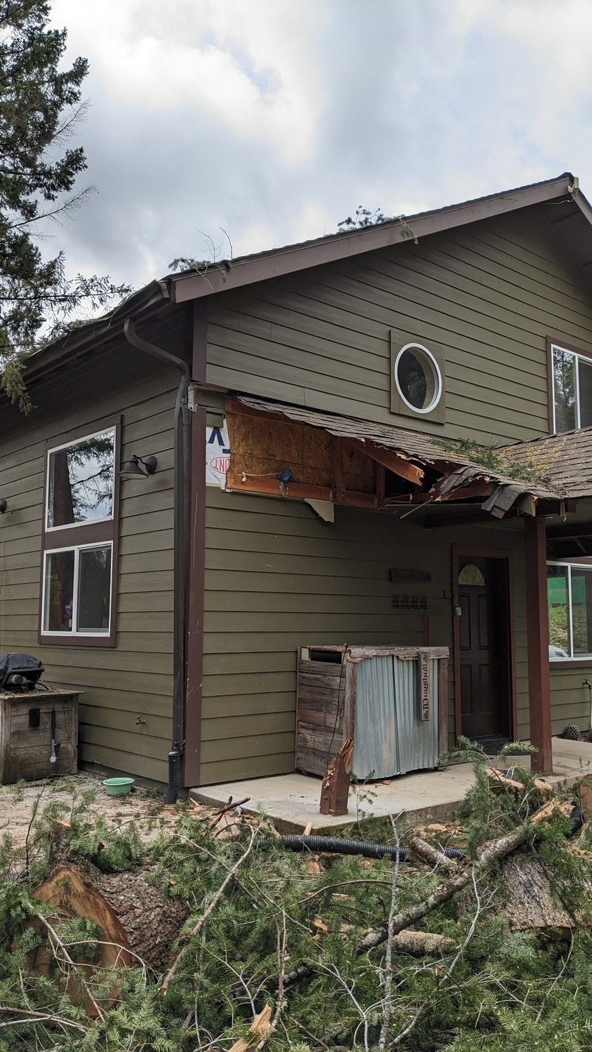 Storm damage to home exterior with torn soffit and exposed sheathing before repair