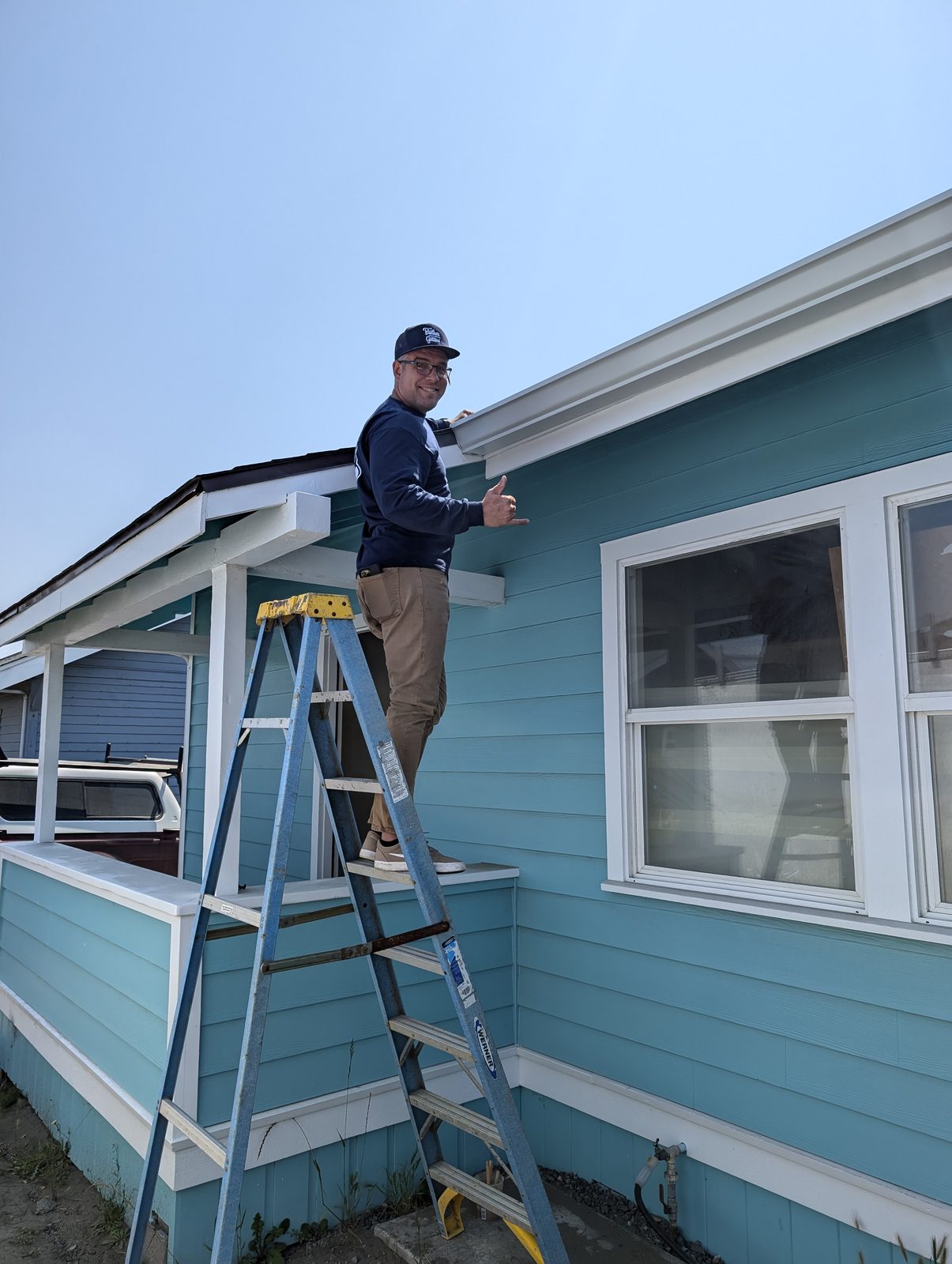 NorCal Exterior crew member completing siding repair work on a sky-blue cottage, serving Fortuna and the Eel River Valley